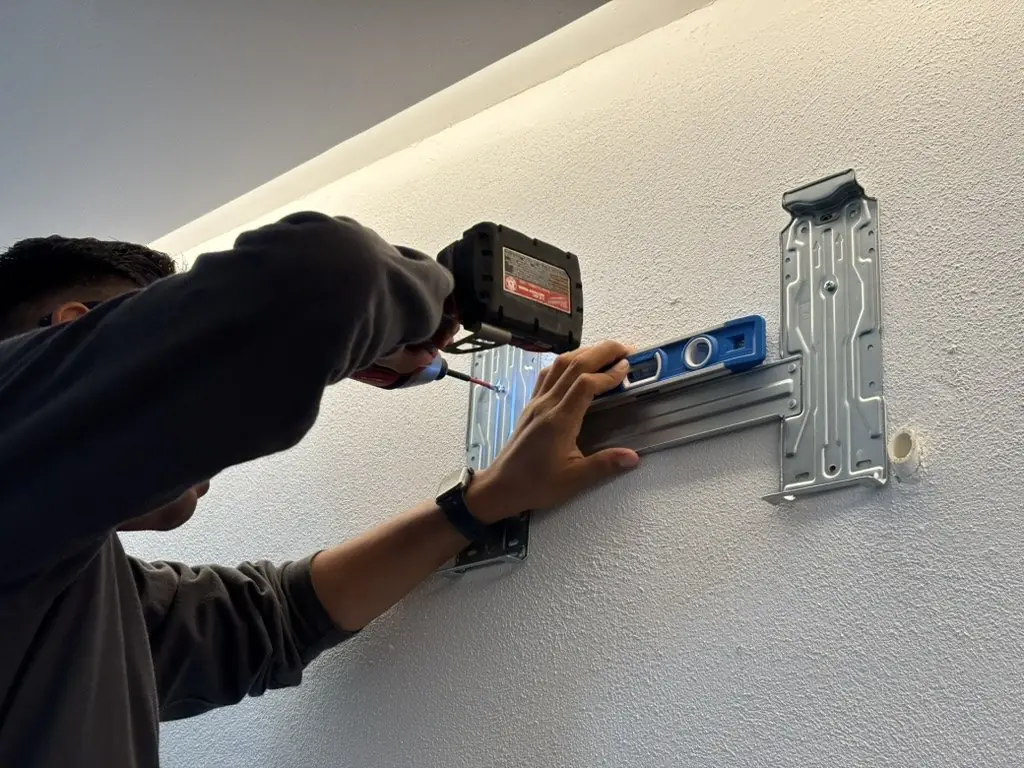 Técnico nivelando y fijando el soporte de una evaporadora en la pared